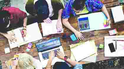 MBA students collaborating together with a Laptop, Tablet and class notes