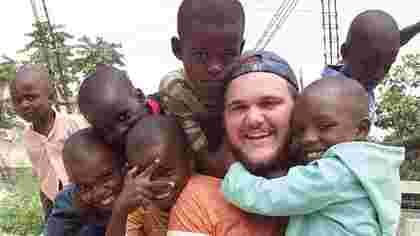 Student on a missions trip in a group hug with kids